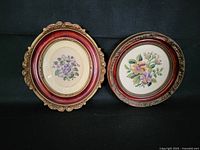 Two framed needlework artworks showing overall presentation, one oval with purple flowers and one round with multicolor flowers.