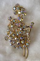Front of vintage rhinestone floral brooch showing clear rhinestones with iridescent shine on gold-tone metal base.