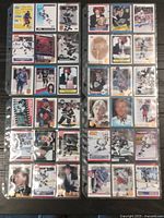 Two-page spread of hockey cards featuring Wayne Gretzky in plastic sleeves within a card binder, showing a variety of cards from different years and teams.