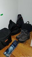 Photo showing three black travel bags and a pair of gray and black mountain boots on hardwood floor with Medipeds arch supports package in front.