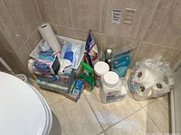 Photo showing corner arrangement of assorted bathroom items including Lysol spray, Epsom salts, tissues, and cleaning products.