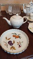 Bowring ceramic teapot with script design and Royal Worcester Evesham tart/quiche plate with painted fruit motif on a table.