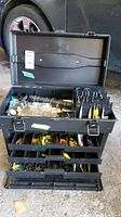 Opened fishing tackle box showing assortment of lures, lines, and accessories organized inside multiple trays and compartments.