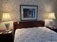 Pair of ceramic table lamps on bedside tables with wood headboard and floral wallpaper in background