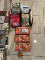 Multiple packs of decorative paper napkins in various designs and colors arranged on the floor, including reds, greens, and floral patterns.