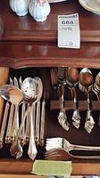 Drawer with sets of spoons including teaspoons and soup spoons, plus forks with detailed handle designs.