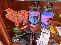 Pink ceramic piggy bank with floral skirt, mini pen, and two hot flash cooling towels in plastic jars seen on shelf