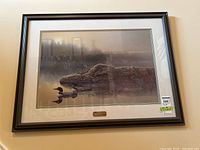 Framed limited edition print signed by Tyler Thompson numbered 81/750, showing natural scene with two loons on water and misty forest background