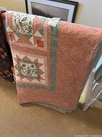 Quilt folded over a rail, showing salmon pink border and patchwork design