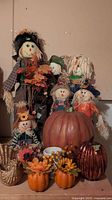 Group photo of the plush scarecrows, decorative pumpkins, wicker bird, and ceramic container showing all items together.