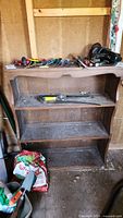 Front view of the wooden shelving unit showing three shelves with some tools and other items on top and shelves.