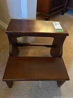 Top-down view of wooden step stool showing two steps and visible surface scratches on the top step.