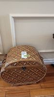 Front view of the dome-shaped wicker style wood storage box with lid and metal handles.