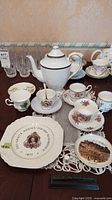Photo showing assortment of teacups, saucers, a white Spode coffee pot, and various decorative plates including one marked 'Lord Nelson'