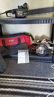 Porter Cable cordless circular saw PCC661 without battery, Porter Cable tool bag, Remington 14 inch limb and trim electric chainsaw on shelf.