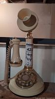 Full view of vintage candlestick rotary telephone showing ivory handset and upright mouthpiece connected to base with rotary dial.