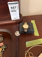 Two ladies fashion wristwatches placed on a wooden surface with some jewelry visible in the background.