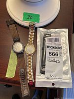 Overview photo showing all three items on a dark wooden surface: Timberland watch, Citizen watch, and packaged Timex band.