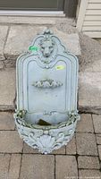 Front view of the resin wall-mounted water fountain showing lion head, scalloped basin, and ornate lower basin.