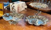 Photo of both Art Deco lady figural dessert trays showing metal cutout plates, bases and figurines.