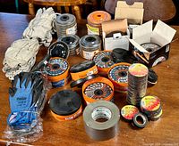 Overall lot showing grinding wheels, gloves, 3M Temflex electrical tape, and duct tape on wood table