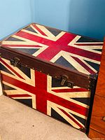 Side view of the trunk showing the Union Jack flag design and metal latch locks with leather trim and rivets.