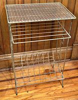 Front view of vintage metal wire stereo and vinyl record holder, showing lattice top shelf and wire record compartments.