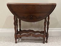 Front view of folded drop leaf walnut table showing carved wood detail and legs