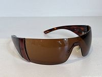 Front view of Bolle Flash sunglasses showing brown lens and dark tortoise frame with matte metallic accents near ear piece.