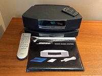 Front view of Bose Wave Music System main unit stacked with CD changer; small remote placed on top