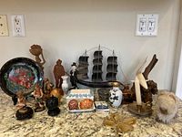 Overview of the entire lot showing various small decorative items arranged on a marble surface against a white wall with electrical outlets.