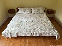 Front view of king sized bed made with white floral duvet cover and two matching pillow shams, showing full bedspread and pillows.