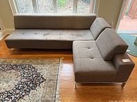 Overall view of L-shaped sectional sofa showing tufted seat cushions and aluminum legs.