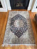 Full view of rug laid on hardwood floor in front of fireplace.