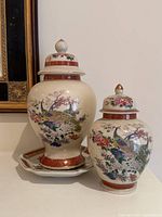 Two lidded Satsuma-style ceramic ginger jars and matching hexagonal ceramic decorative plate displayed together, showing overall design and relative sizes.