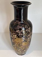Front view of the vase showing floral design with gold chrysanthemums and leaves on black porcelain.