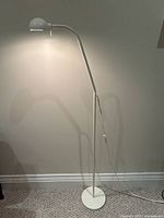 Full view of the tall cream-colored floor lamp standing on carpeted floor showing its minimalist design.