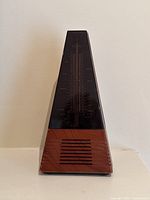 Front view of vintage Seiko Ictus Quartz metronome showing black tinted face with tempo scale and wooden pattern plastic speaker section at bottom.