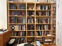Full front view of all four shelving modules against wall, fully stocked with books and media.