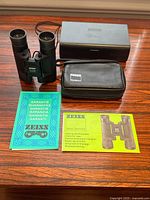 All included items laid out: binoculars, leather pouch, hard case, manual, warranty card