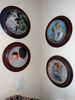 Four framed display plates mounted on walls in a corner, showing various child and nostalgic themes
