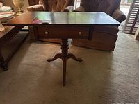 Antique wooden drop leaf end table shown with leaves extended and drawer visible.