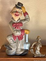Photo showing the clown figurine vividly with detailed colors and the small metallic hobo figurine beside it