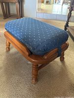 Side angled view showing turned legs and wood finish with attached blue cushion.