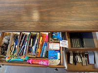 View of an open desk drawer containing various office supplies.