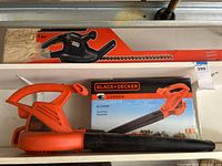 Photo showing Black & Decker hedge trimmer in box and Black & Decker corded electric blower with box below.