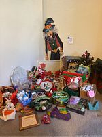 Wide view showing numerous holiday-themed decorations including Halloween witch hanging figure, Christmas, Halloween, Fall, and St. Patrick's Day items variously arranged on floor and shelf.