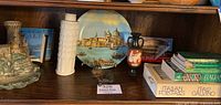 Shelf display of Italian memorabilia including ceramic plate, vase, figurines, books, and brass dish