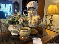 Photo of Emilio Fiaschi bust sculpture and two decorative planters on wood table with lamp and furniture background