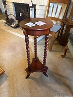 Photo of the mahogany plant stand showing round top, barley twist legs, tripod base, brass hardware, light discoloration